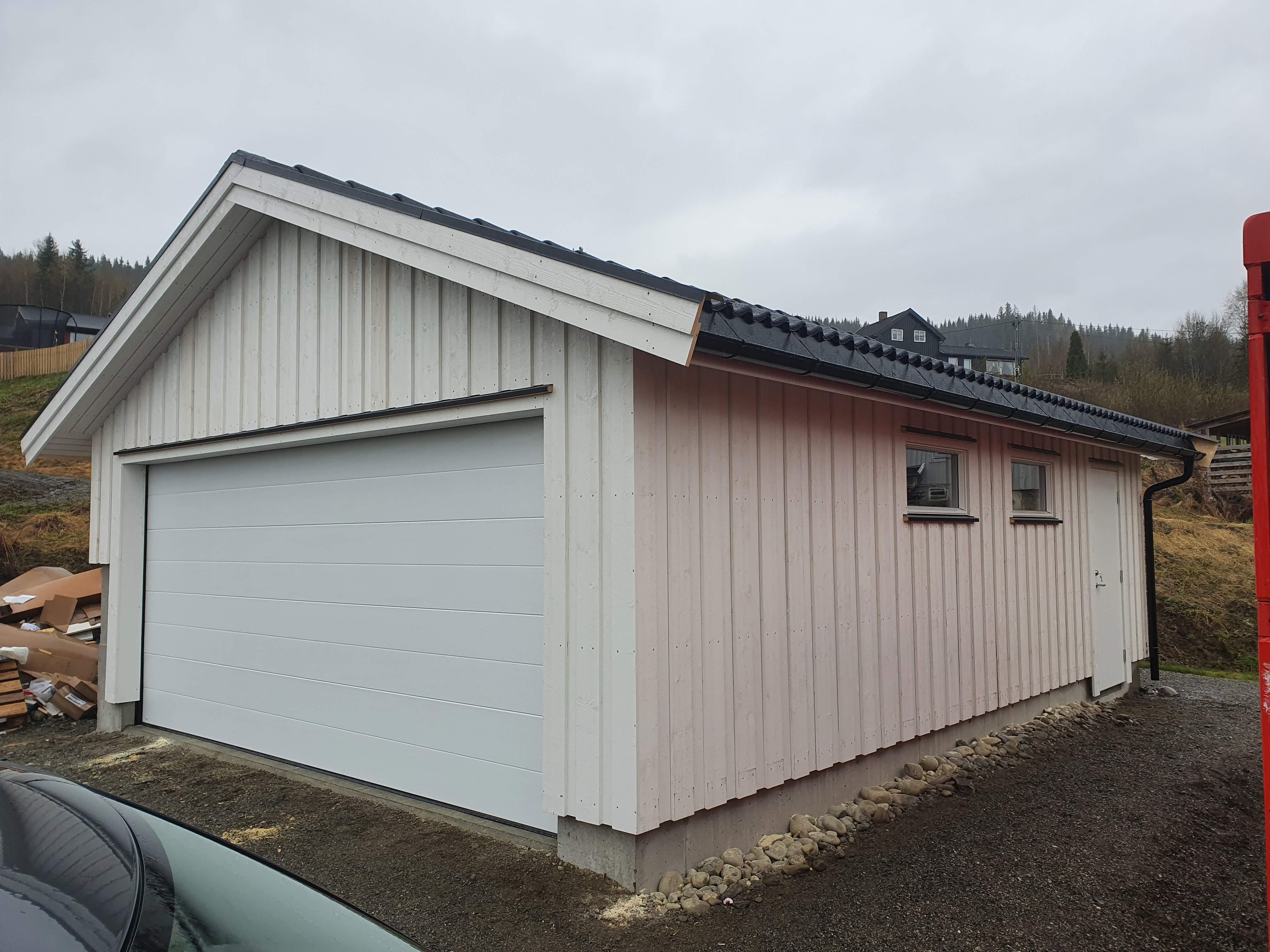 Hvit garasje med stående panel og hvit leddport