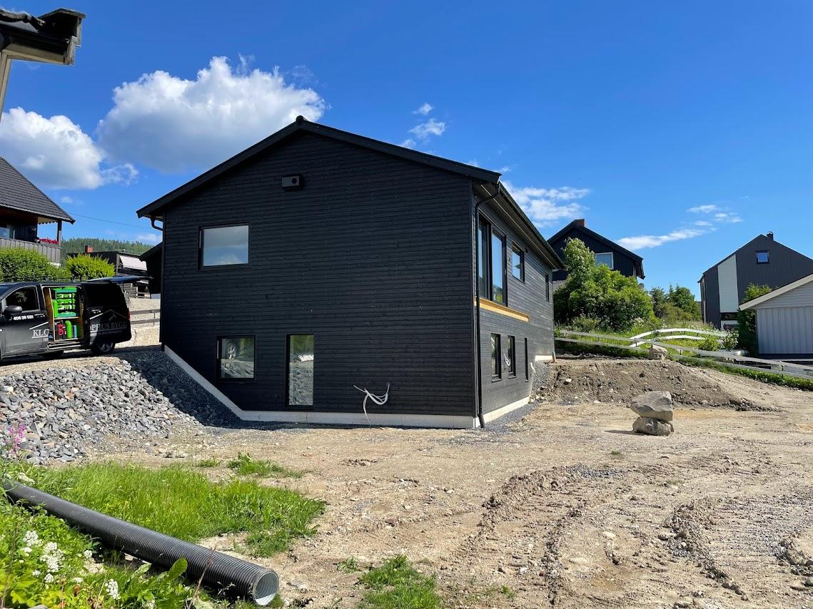 Nytt hus med svartbeiset stående panel, sett fra hjørnet